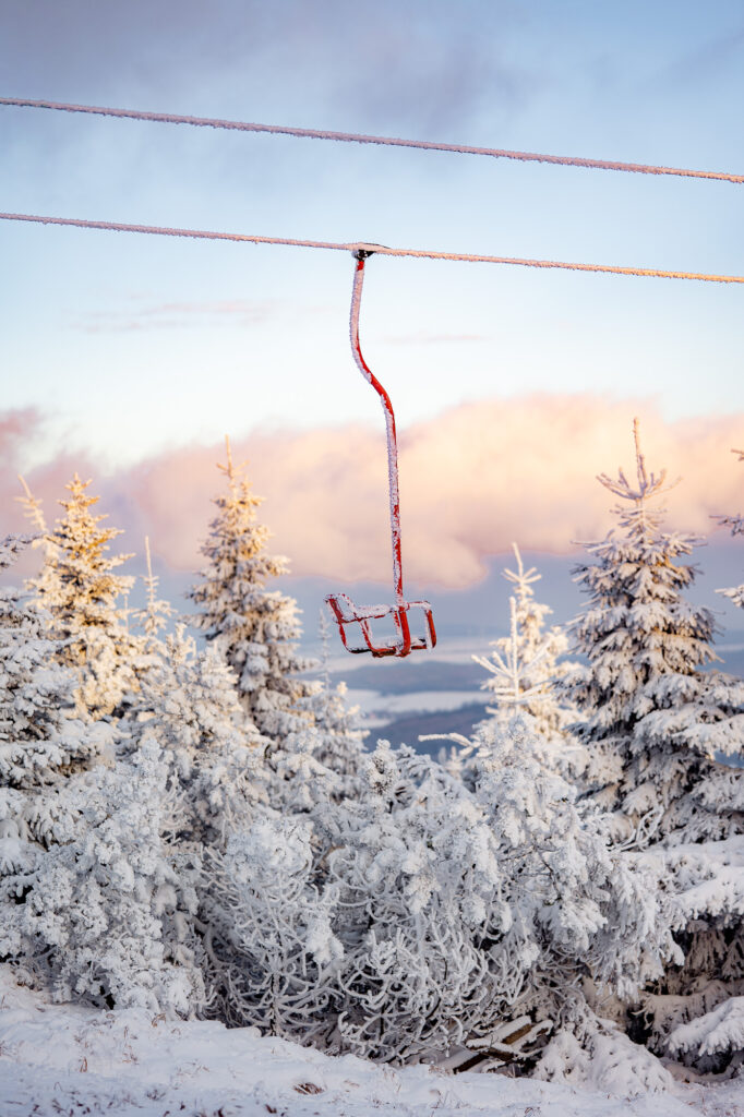 tief verschneiter roter Sessellift am nostalgischen Sessellift auf dem Fichtelberg im Erzgebirge
