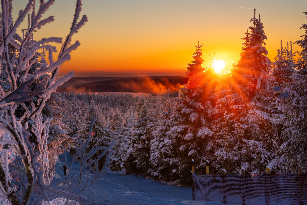 Sonnenuntergangsstimmung auf dem Fichtelberg im Erzgebirge mit untergehender Sonne und Nebelschwaden